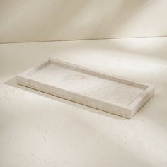 a white marble tray sitting on top of a table next to a wall with light coming in through the window