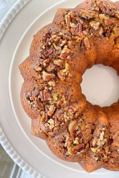 a bundt cake on a white plate topped with nuts