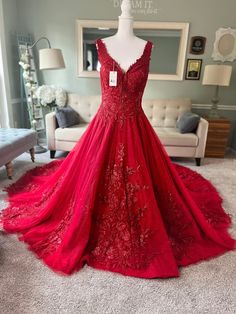 a red prom dress on display in a room with a couch and chair behind it