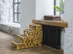 a wooden stair case next to a brick wall with windows and a plant in it