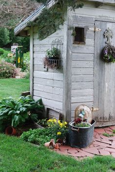 an outhouse with potted plants on the side and a cow statue in front