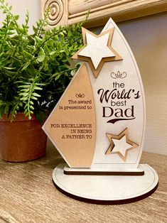 a wooden christmas tree with stars on it sitting next to a potted green plant