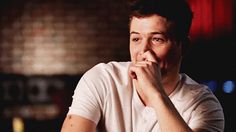 a man sitting at a table with his chin resting on his hand and looking to the side