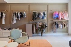 a room filled with lots of clothes on shelves next to a white table and chair