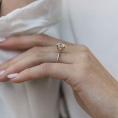 a close up of a person's hand wearing a ring with a heart shaped diamond