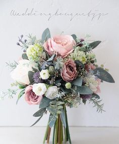 a bouquet of flowers sitting on top of a white table next to a sign that says, wedding bouquets