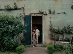 two people are standing in the doorway of an old building with vines growing on it