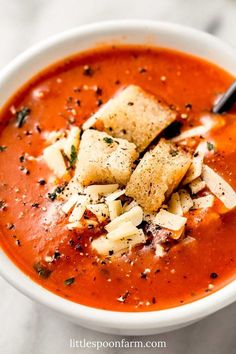 a bowl of homemade tomato soup with croutons and parmesan cheese