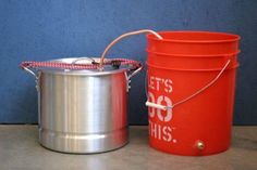 two metal buckets sitting next to each other on a table with a blue wall in the background