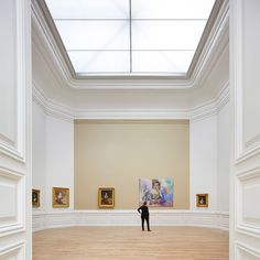 a person standing in an empty room with paintings on the walls