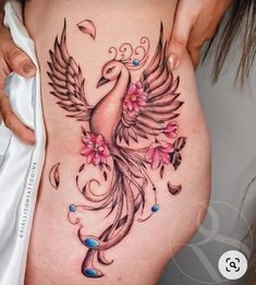 a woman's stomach with a bird and flowers tattoo on the side of her belly