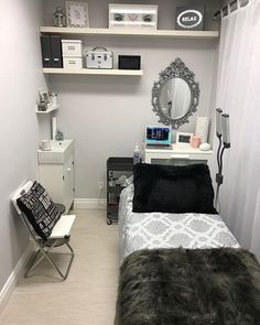 a small room with a bed, desk and mirror