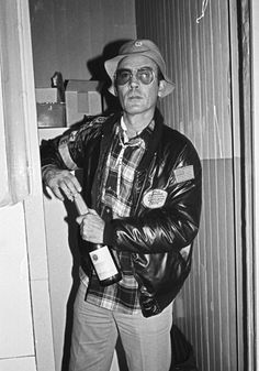 a man in a leather jacket holding a bottle