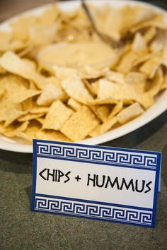 a plate with chips and hummus on it next to a sign that says chip's + hummus