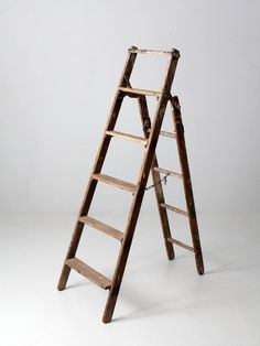 an old wooden ladder leaning against a white wall