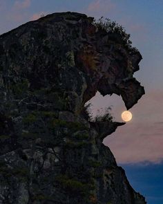 the moon is setting behind a rock formation