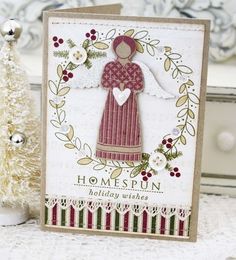 a christmas card with an angel holding a heart in front of a small white tree