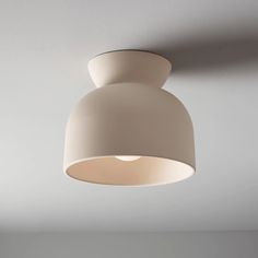 a white light hanging from the ceiling in a room with gray walls and flooring