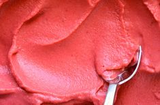 a close up of a spoon in a bowl with red food coloring on the surface