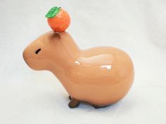 a small toy animal with an orange on its head