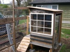 a chicken coop in the yard with a window on it's side and a door open