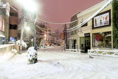 a snow covered street with buildings and lights