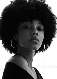 a black and white photo of a woman with large hoop earrings on her head, looking off to the side