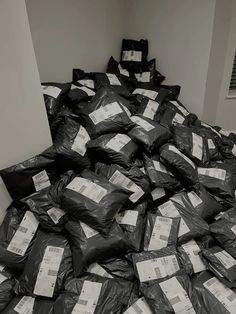 a pile of black bags filled with lots of papers sitting on top of a floor