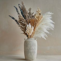 a vase filled with lots of different types of dried flowers in it's center