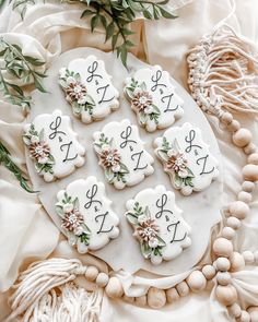 decorated cookies on a white platter surrounded by beads and greenery