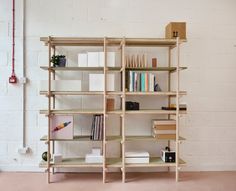 a bookshelf with many different types of books on it in front of a white brick wall