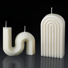 two candles are next to each other in the shape of letter j, and one candle is shaped like an oar