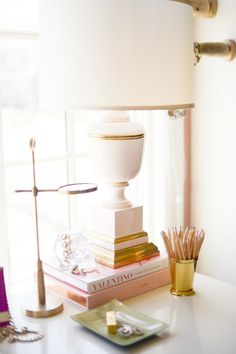 a white lamp sitting on top of a table next to a stack of books and pencils