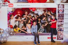 a group of children standing in front of a photo booth with balloons and streamers