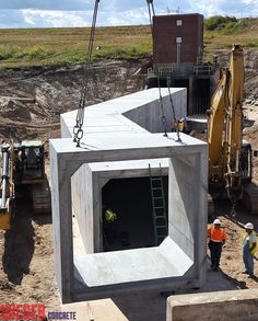 construction workers stand in front of a large concrete structure that is being built into the ground