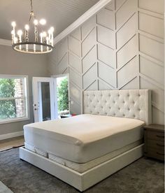 a white bed sitting in a bedroom under a chandelier