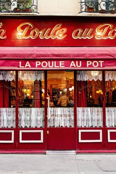 a store front with red awnings and white drapes on the windows that read la poule au pot