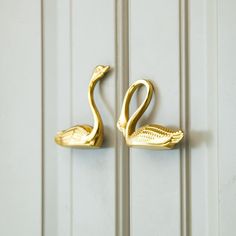 two gold swan hooks on a white door