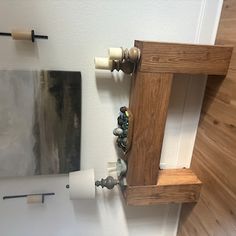 a bathroom with a toilet, mirror and wooden shelf on the wall next to it