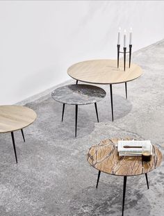 three tables with candles on them sitting in front of a white wall and grey carpet