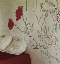 a bed sitting next to a wall with flowers painted on it