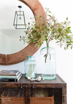 there is a vase with flowers on top of the table next to a mirror and some books