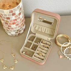 an open jewelry case sitting on top of a table next to bracelets and rings