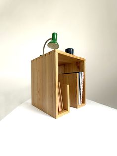 a wooden box with a lamp and books in it on a white surface, against a plain background