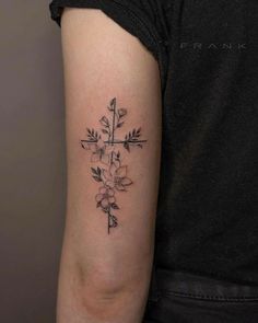 a cross tattoo with flowers on the upper half of the arm and behind it is an arrow