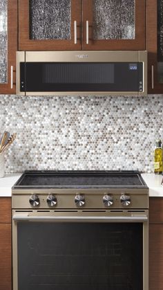 a stove top oven sitting inside of a kitchen next to wooden cupboards and white counter tops