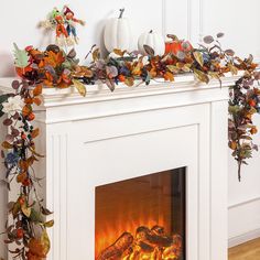 a white fireplace decorated with autumn leaves and pumpkins