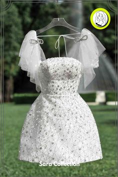 a wedding dress hanging on a hanger in front of a park with trees and grass