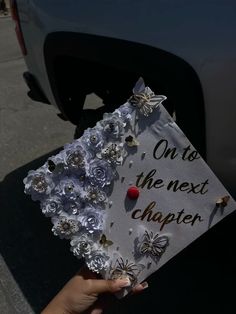 someone holding up a graduation cap that says on its the next charter with flowers and butterflies