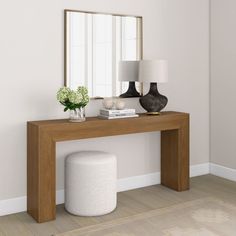 a white vase sitting on top of a wooden table next to a mirror and lamp